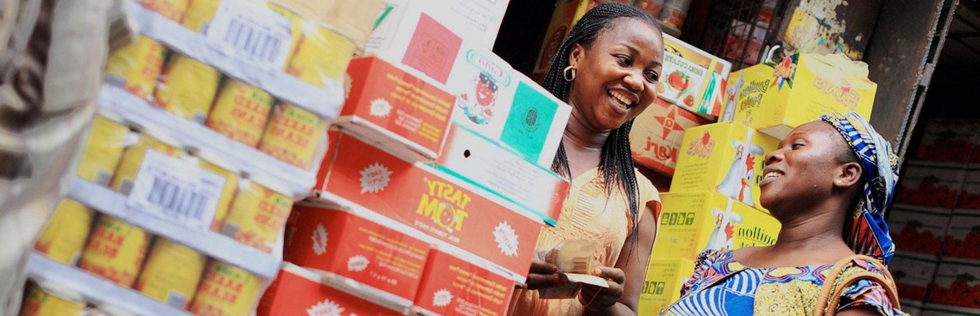 尼日利亚推荐买球平台，一位顾客在她的摊位上从店主那里购买包装食品. 